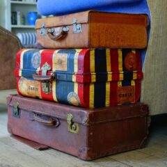 A small stack of of carry-on luggage on top of larger travel cases.