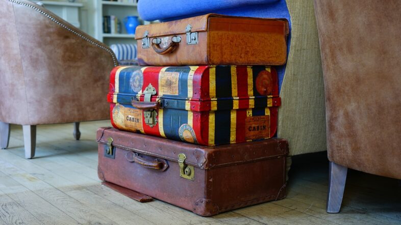 A small stack of of carry-on luggage on top of larger travel cases.